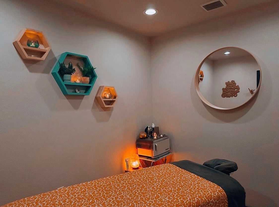Cozy massage room with warm lighting and decorative shelves.