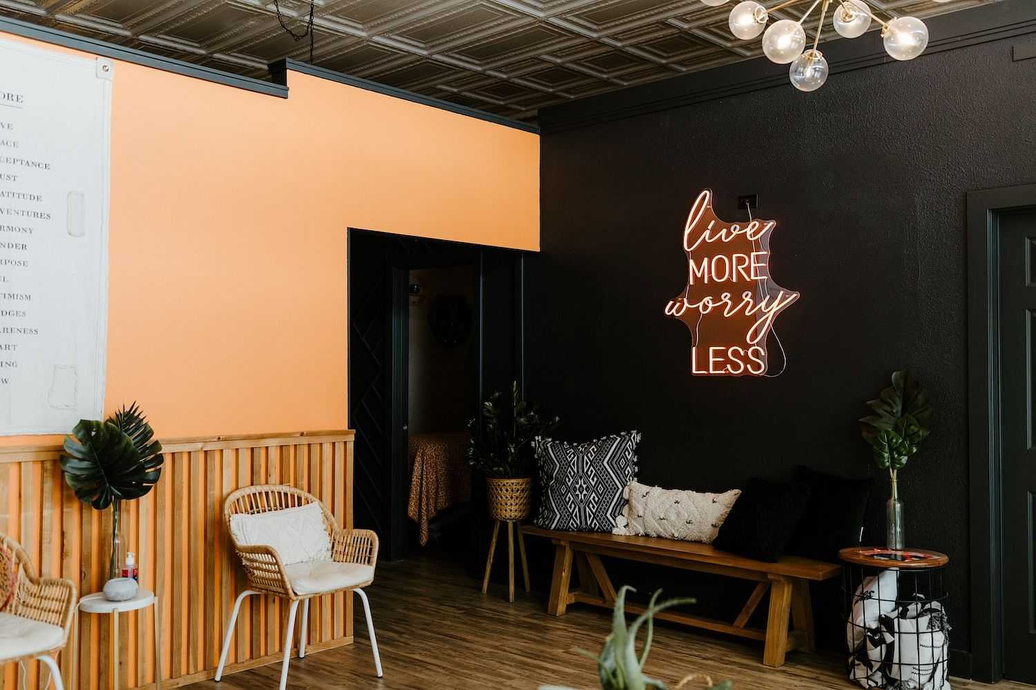 Neon sign on a wall reading 'Live More Worry Less' in a stylish indoor setting.