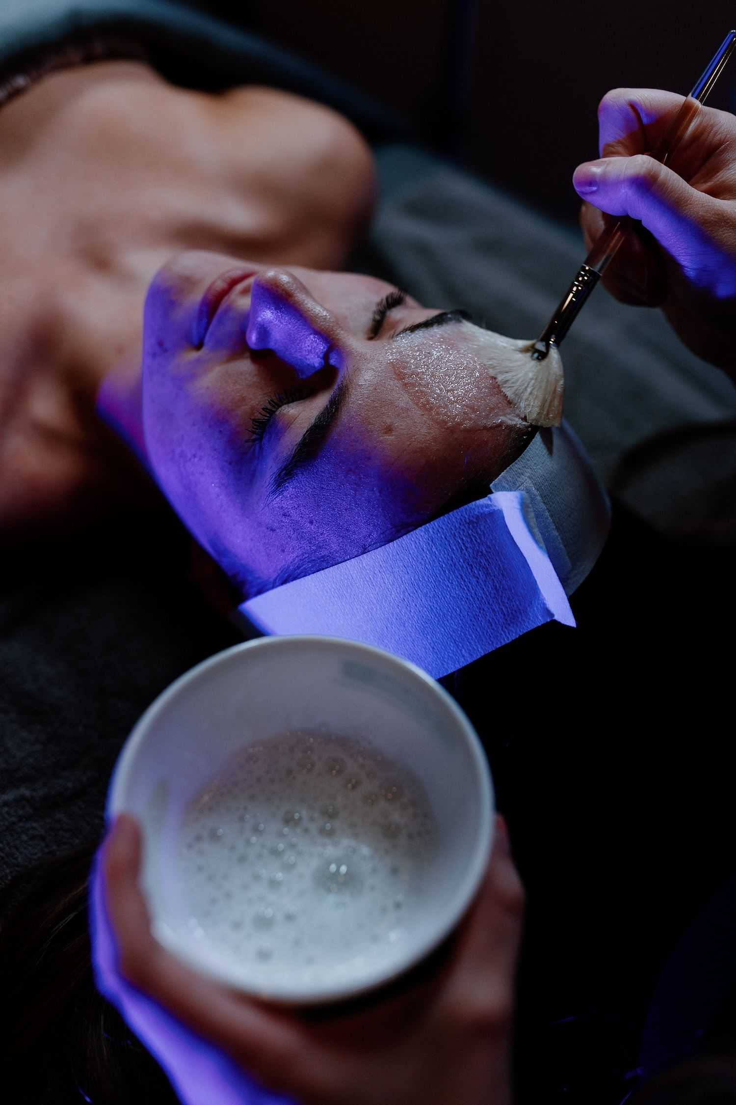 Person receiving a facial treatment with a purple mask.