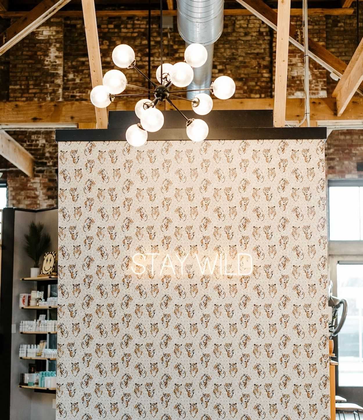Wall divider with "STAY WILD" text under a modern chandelier.