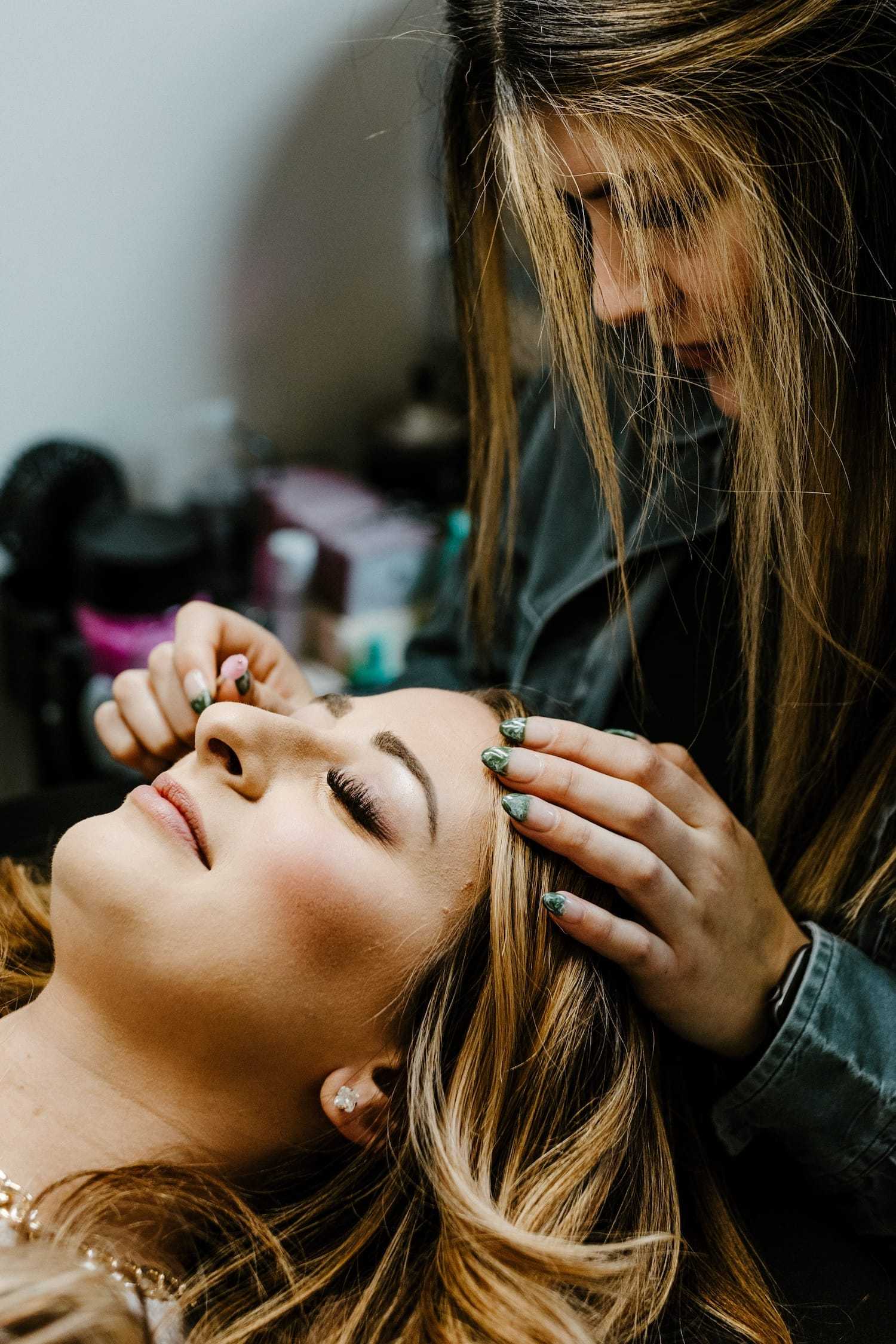 Makeup artist applying eyeliner to a woman in a salon.