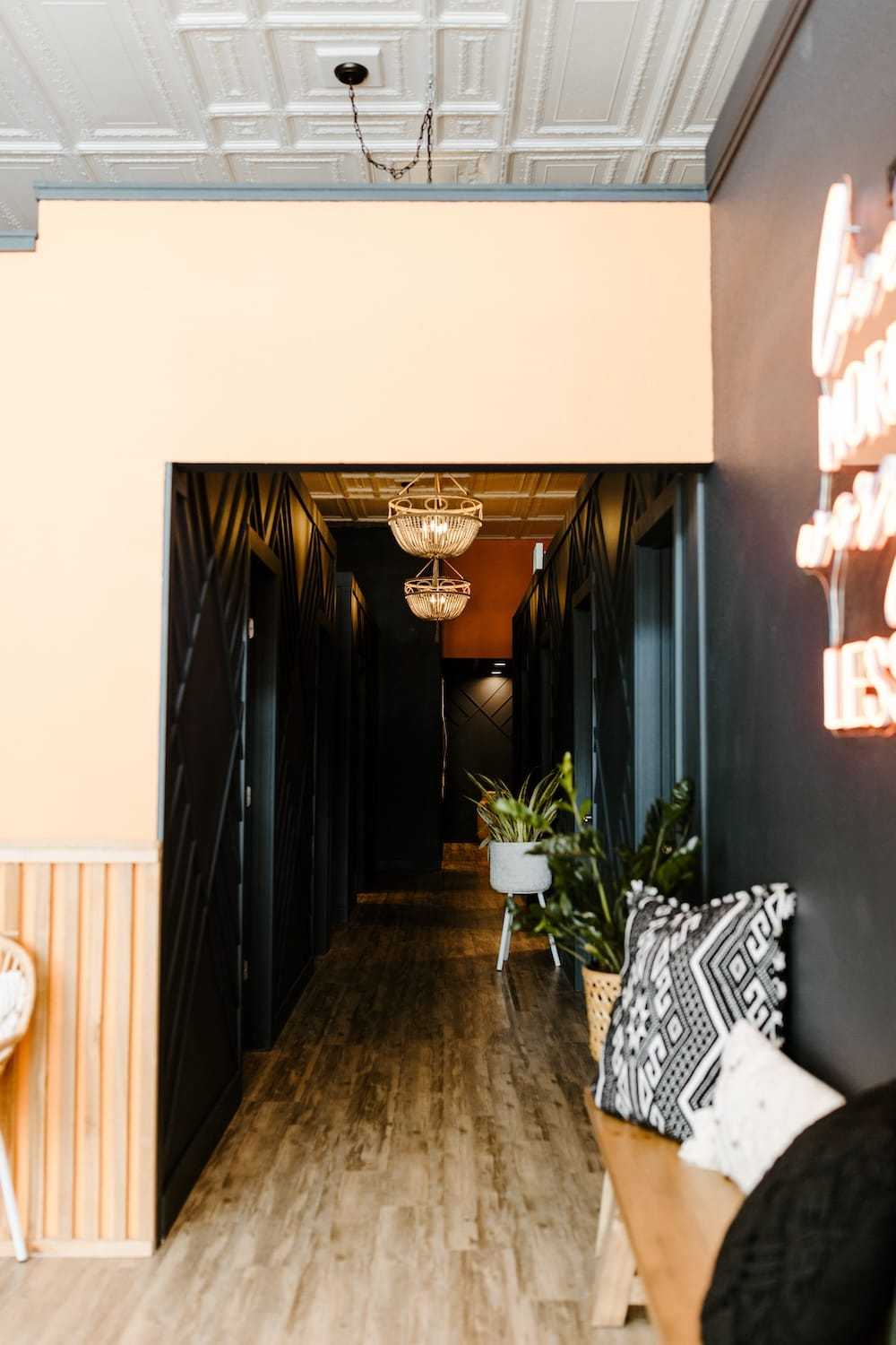 Hallway with wooden floors, pendant lights, and neon sign on right.